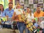Montagem de premia&ccedil;&atilde;o de caf&eacute;s com mulher segurando certificado e trof&eacute;u dourado, grupos reunidos e entrega de cheques.