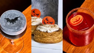 Montagem de Halloween com coquetel cinza decorado com morcego, doces com rostos de abóbora e bebida vermelha com decoração de abóbora.