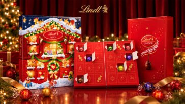 Calendários do Advento Lindt Teddy e Lindor, com janelinhas numeradas e bombons coloridos, diante de decoração natalina.