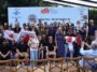 Grupo de participantes posa diante de painel do Rio Coffee Nation, com algumas pessoas segurando placas e certificados.