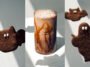 Montagem com biscoitos escuros em formato de morcego e fantasma e bebida gelada cremosa com calda nas paredes do copo.