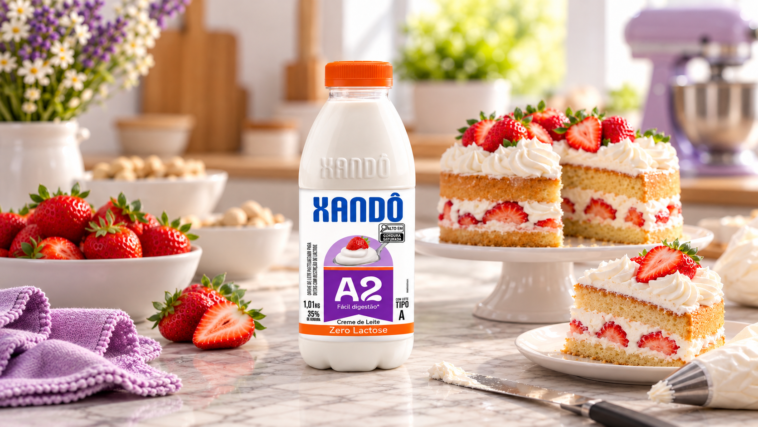 Garrafa de creme de leite A2 zero lactose Xandô diante de fatias de bolo com morangos e cobertura branca.